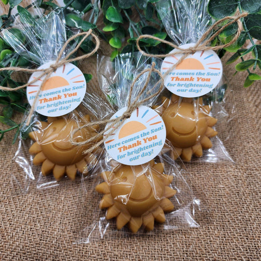 Sun-shaped favors in clear packaging with decorative tags on a textured surface.