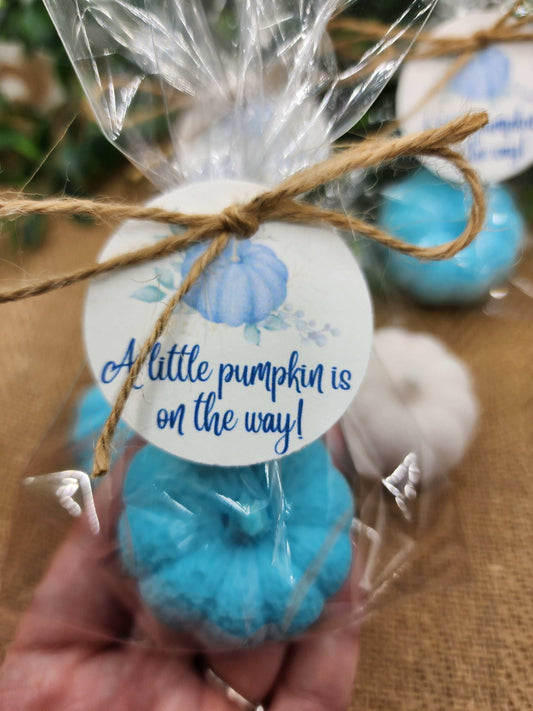 Blue decorative item with a 'A little pumpkin is on the way!' tag, held in a hand.