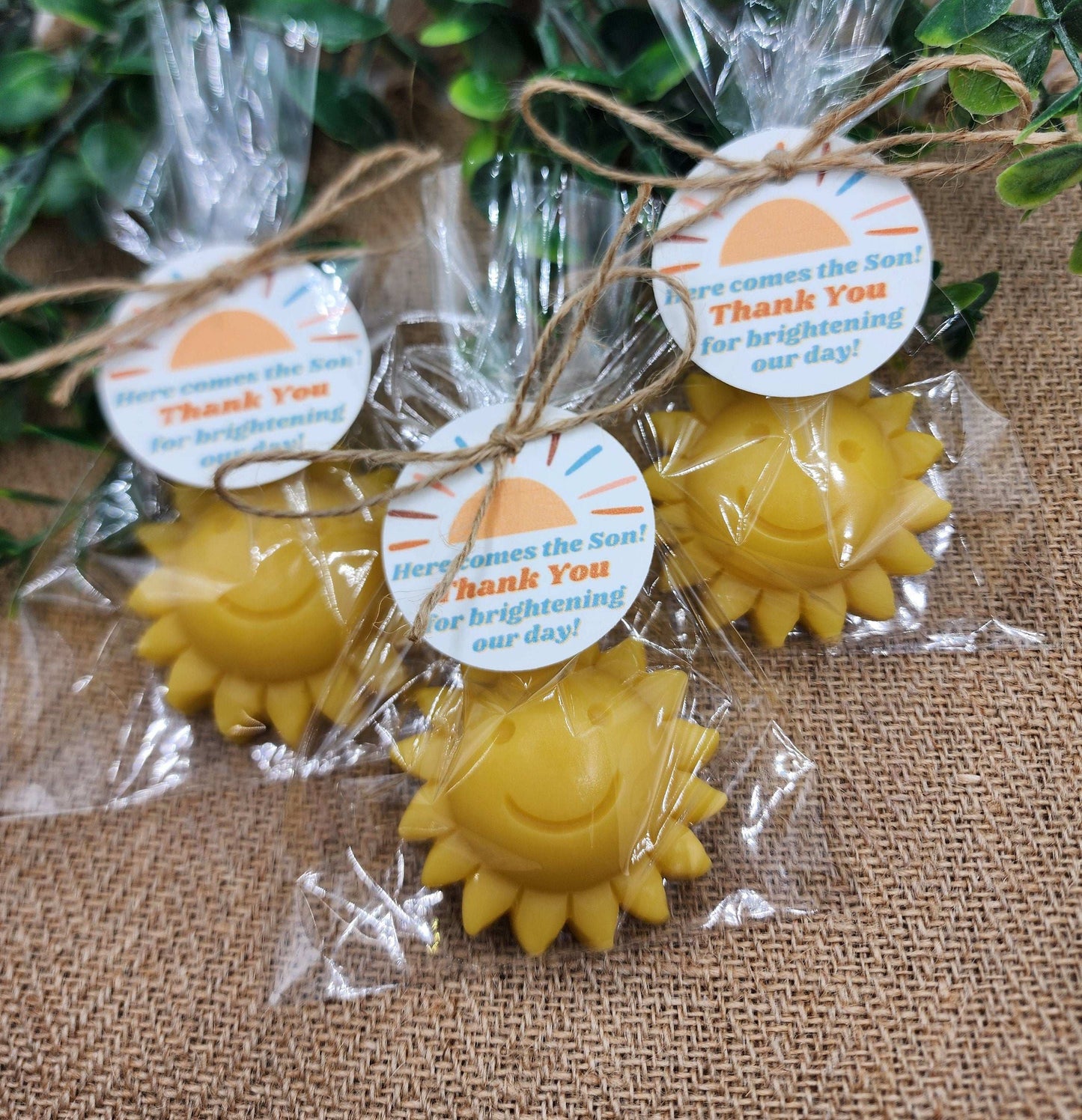Yellow sun-shaped items in clear packaging with 'Thank You' tags on a textured surface.