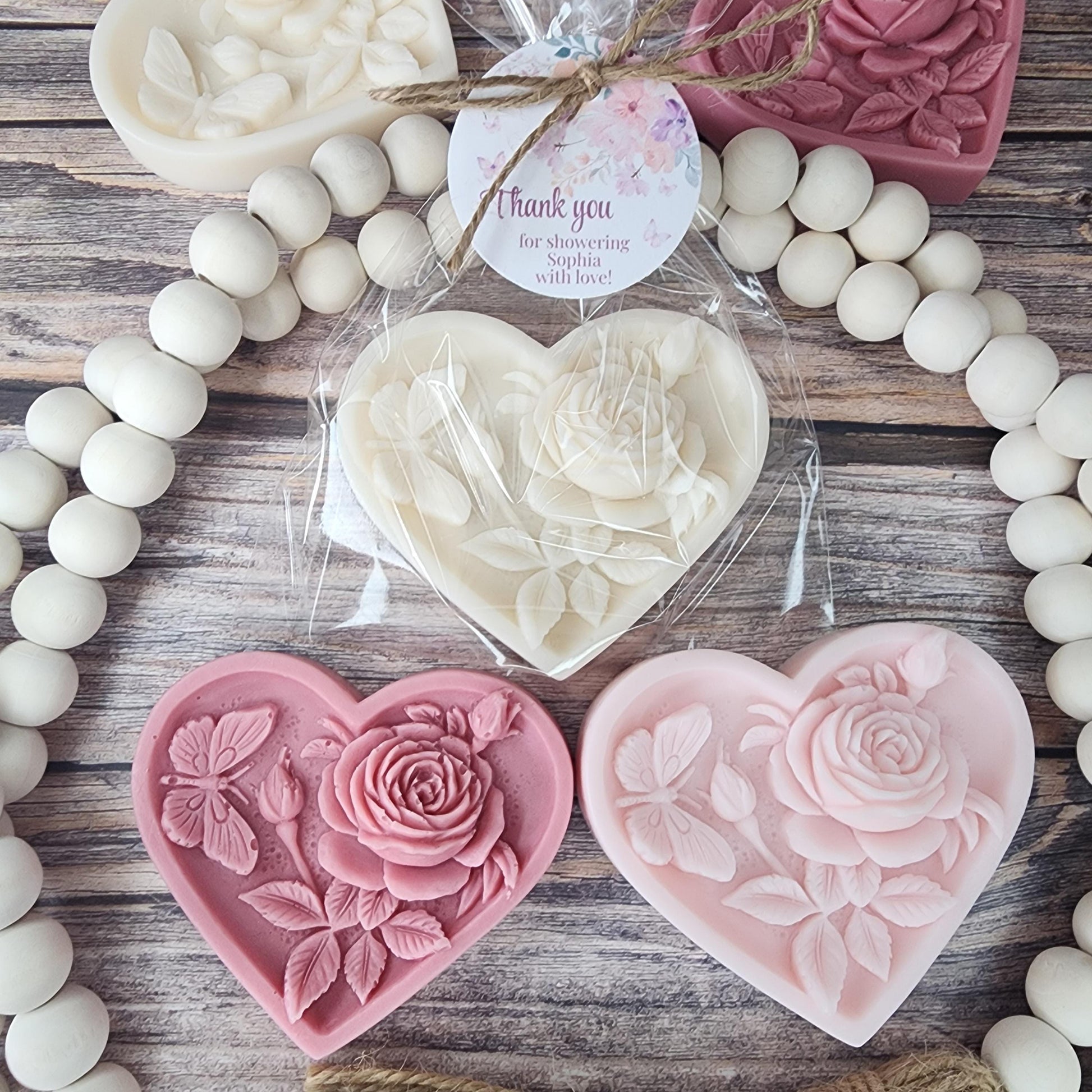 Heart-shaped floral favors on a wooden surface with white beads