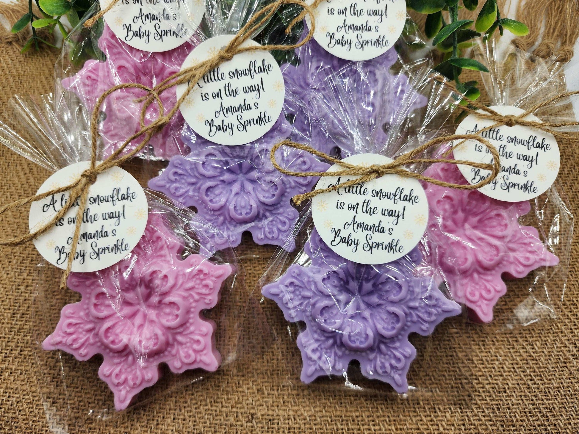 Decorative snowflake-shaped items in purple and pink with labels on a textured surface