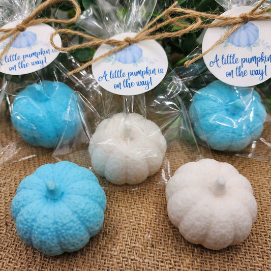 Decorative pumpkins in blue and white with 'A little pumpkin is on the way!' labels on a burlap surface.