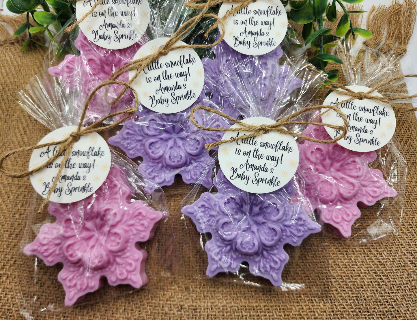 Decorative soap bars in pink and purple with personalized tags on a textured surface.