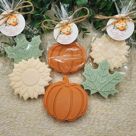 Decorative soap bars shaped like pumpkins, leaves, and sunflowers in clear packaging with labels.