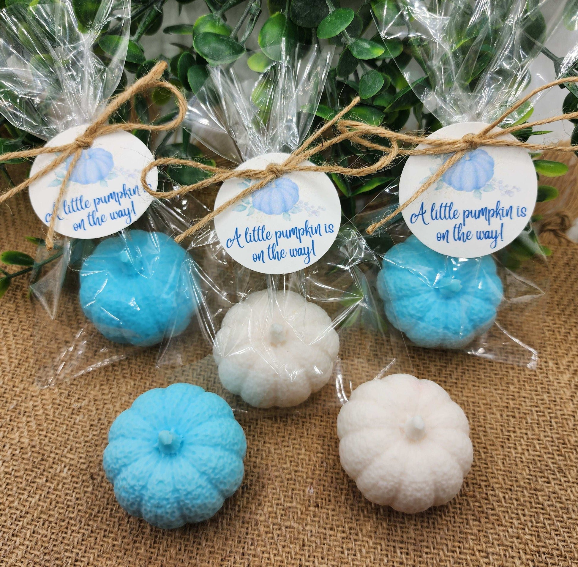 Decorative pumpkins in blue and white with 'A little pumpkin is on the way!' tags on a burlap background.
