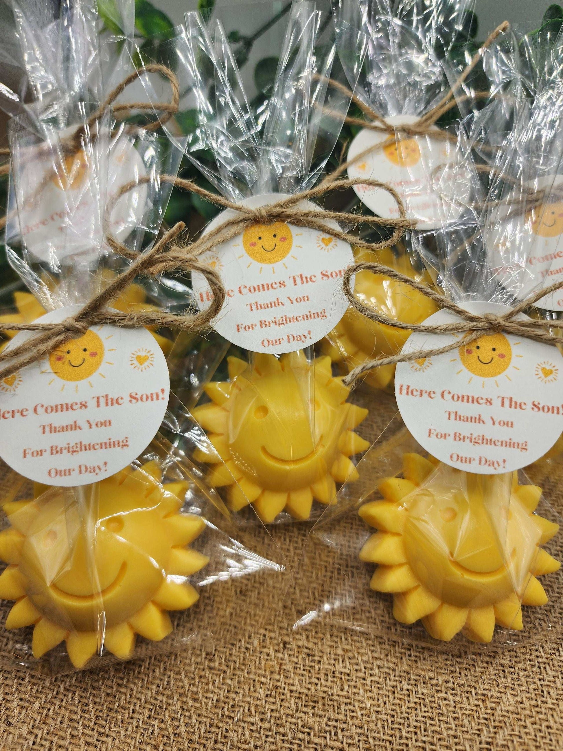 Yellow sun-shaped candles with smiley faces and gift tags on a textured surface.