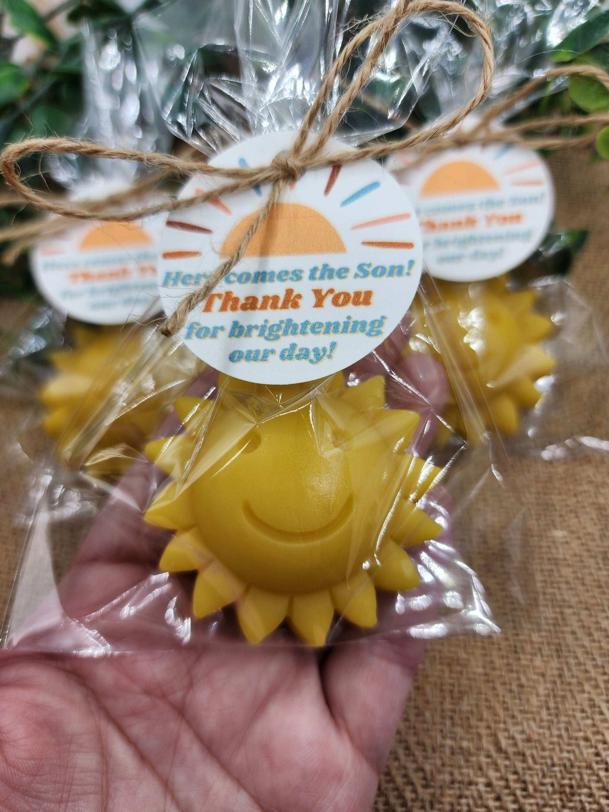Yellow sun-shaped item with a 'Thank You' tag, held by a hand against a textured surface.