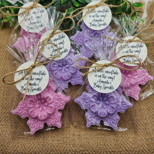 Decorative purple and pink snowflake-shaped favors with tags on a textured surface