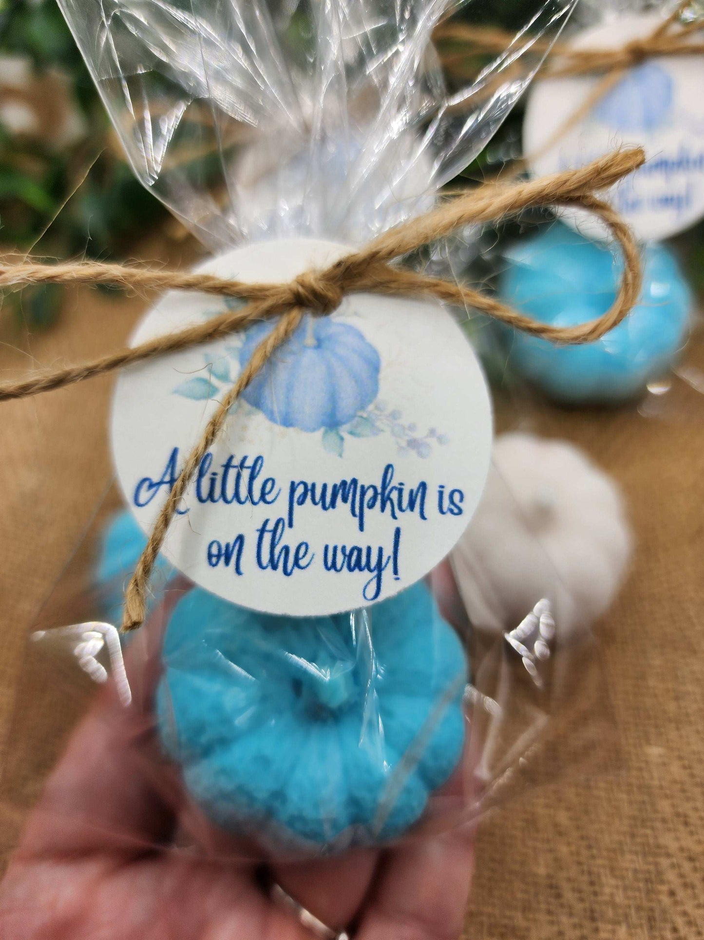 Blue decorative item with a 'A little pumpkin is on the way!' tag, held in a hand.