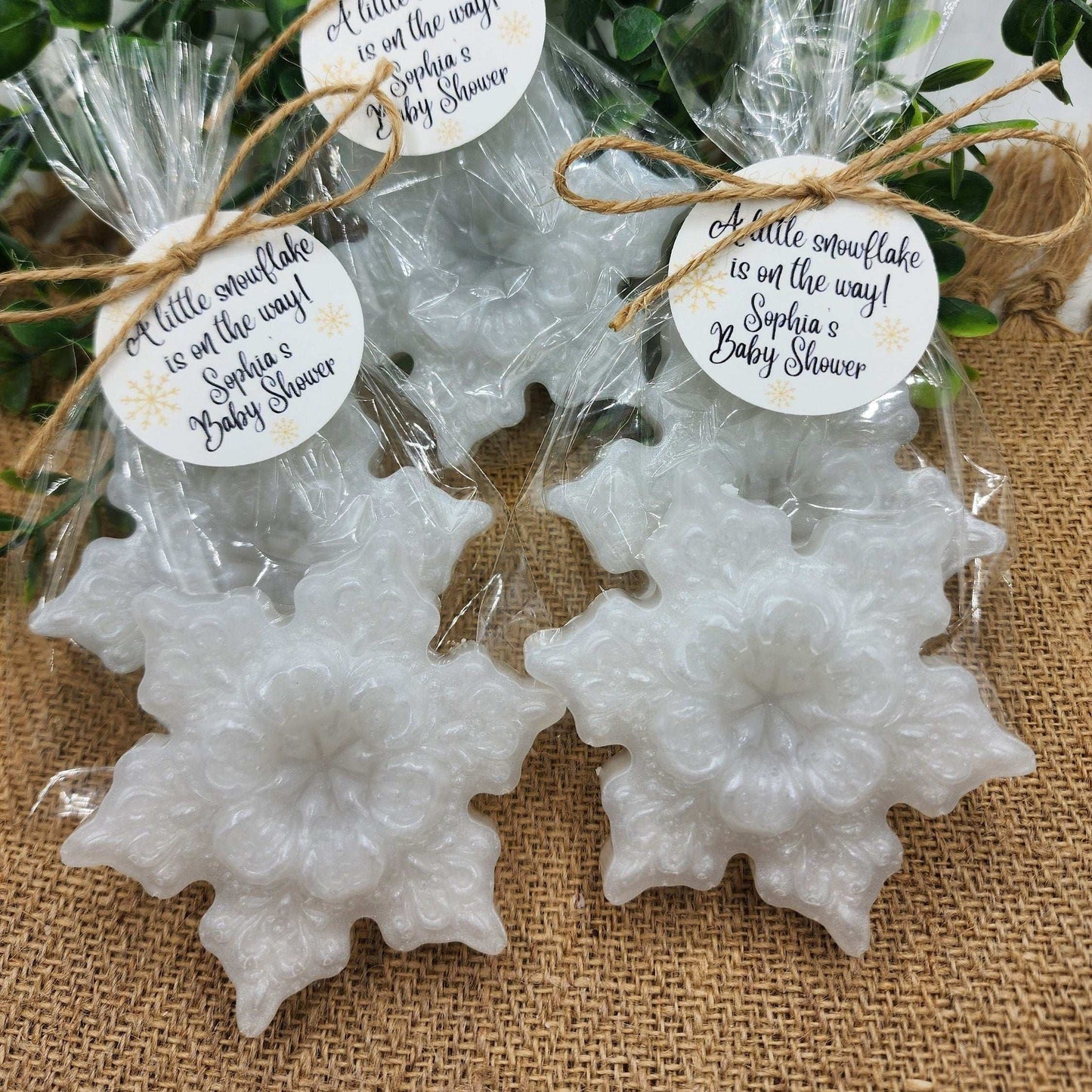 Snowflake-shaped cookies wrapped in cellophane with decorative tags on a textured surface.